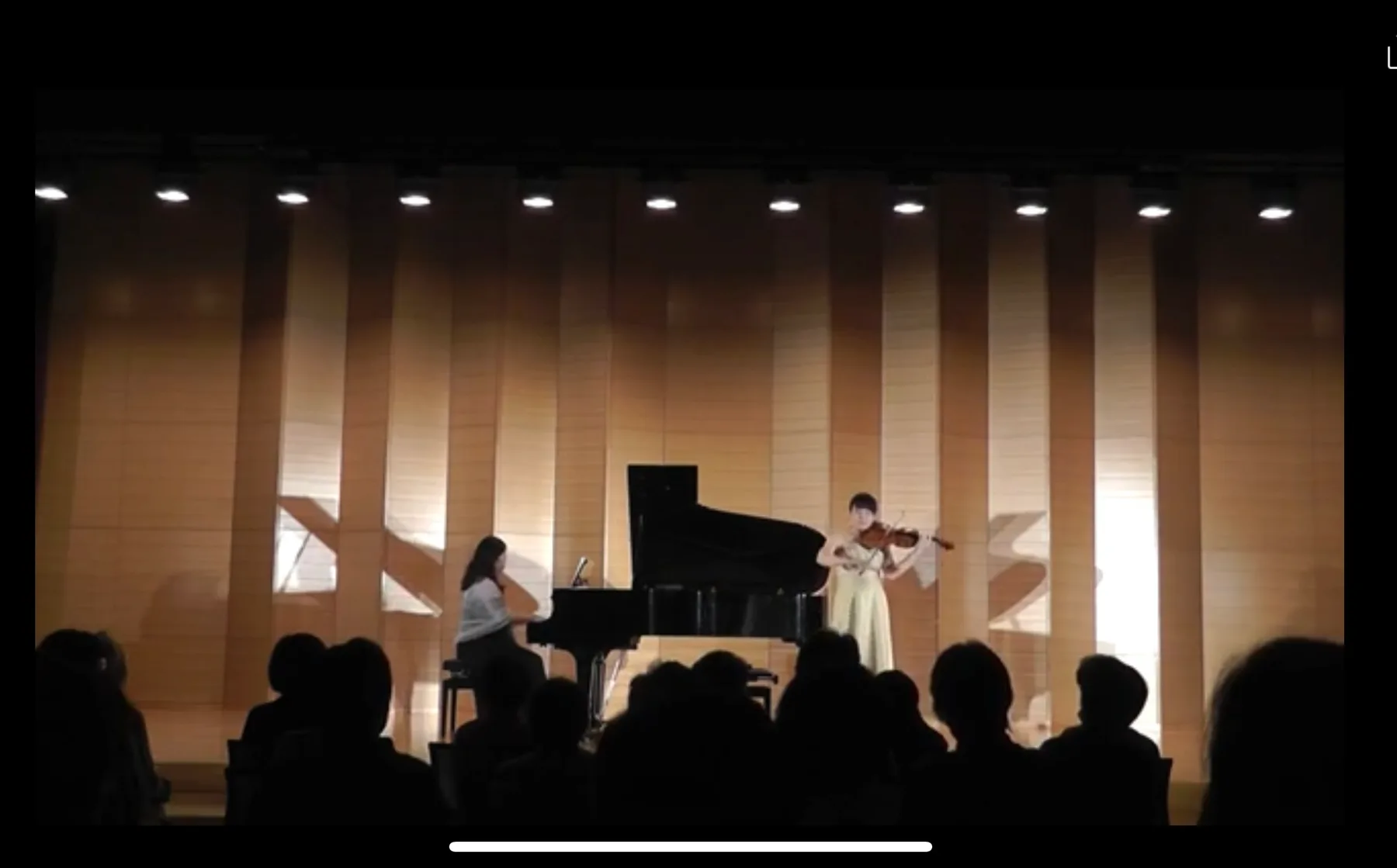 コンサートホールでピアノ伴奏とともに演奏する田中雅子、客席のシルエット