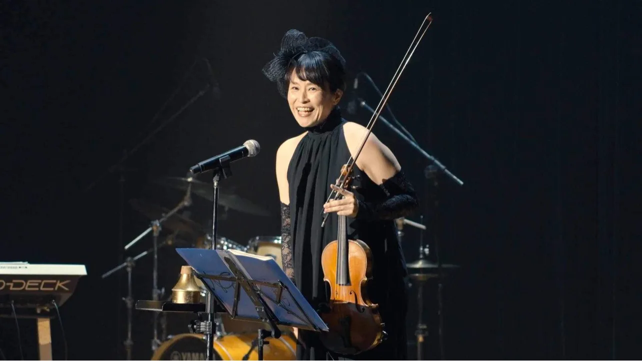 田中雅子がステージでヴァイオリンを構え、笑顔で演奏する様子